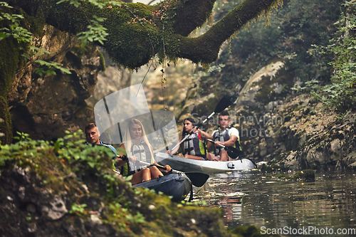 Image of A group of friends enjoying having fun and kayaking while exploring the calm river, surrounding forest and large natural river canyons