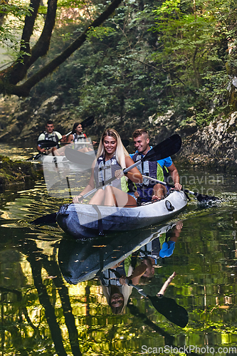 Image of A group of friends enjoying having fun and kayaking while exploring the calm river, surrounding forest and large natural river canyons