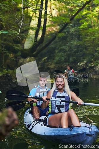 Image of A group of friends enjoying having fun and kayaking while exploring the calm river, surrounding forest and large natural river canyons