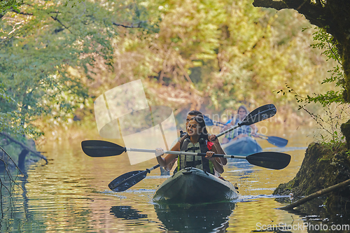 Image of A group of friends enjoying having fun and kayaking while exploring the calm river, surrounding forest and large natural river canyons