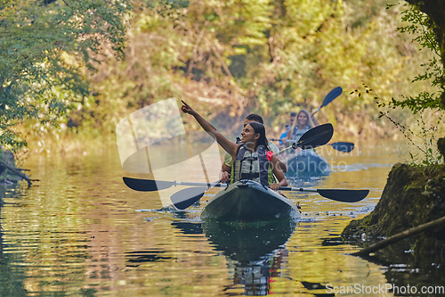 Image of A group of friends enjoying having fun and kayaking while exploring the calm river, surrounding forest and large natural river canyons