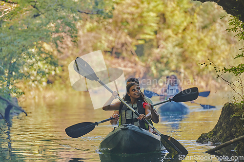 Image of A group of friends enjoying having fun and kayaking while exploring the calm river, surrounding forest and large natural river canyons