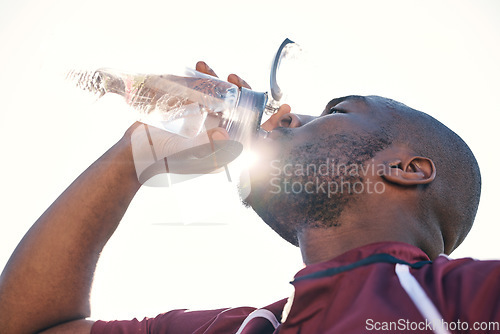 Image of Black man, drinking water and health with fitness, athlete and sports with hydration and sunshine. African male person, beverage in bottle and wellness with exercise, lens flare and low angle