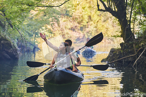 Image of A group of friends enjoying having fun and kayaking while exploring the calm river, surrounding forest and large natural river canyons