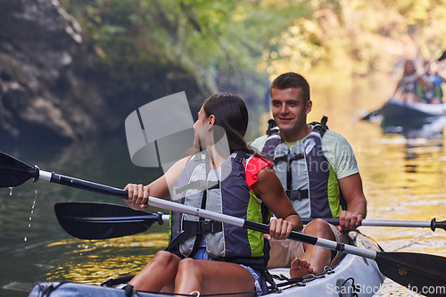 Image of A group of friends enjoying having fun and kayaking while exploring the calm river, surrounding forest and large natural river canyons