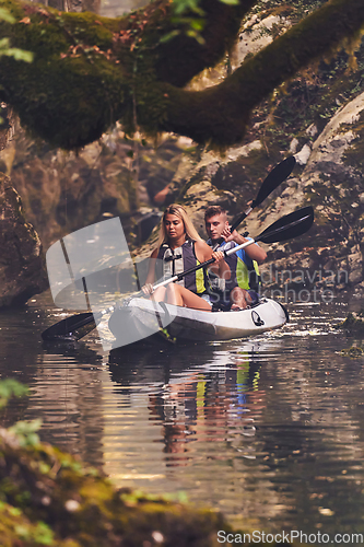 Image of A young couple enjoying an idyllic kayak ride in the middle of a beautiful river surrounded by forest greenery