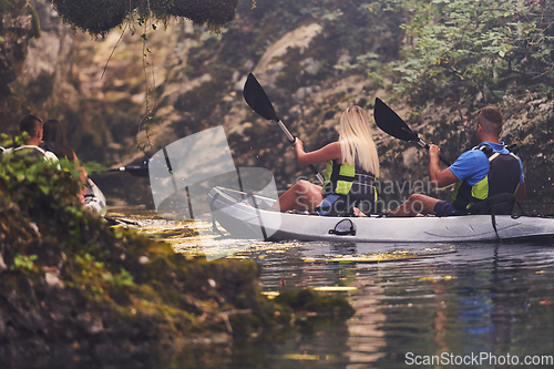 Image of A young couple enjoying an idyllic kayak ride in the middle of a beautiful river surrounded by forest greenery