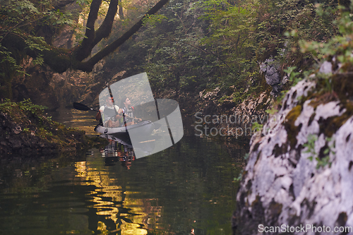 Image of A young couple enjoying an idyllic kayak ride in the middle of a beautiful river surrounded by forest greenery