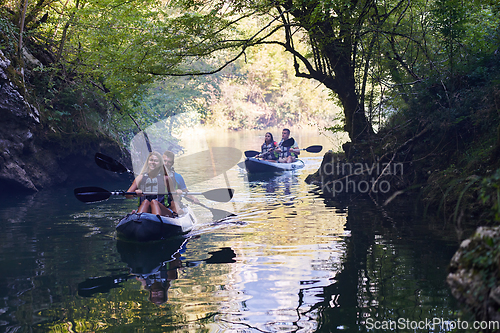 Image of A group of friends enjoying having fun and kayaking while exploring the calm river, surrounding forest and large natural river canyons