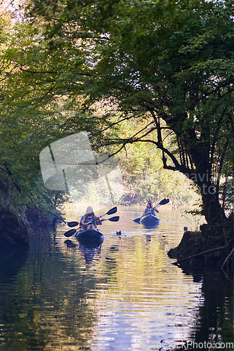 Image of A group of friends enjoying having fun and kayaking while exploring the calm river, surrounding forest and large natural river canyons