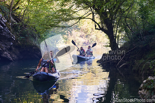 Image of A group of friends enjoying having fun and kayaking while exploring the calm river, surrounding forest and large natural river canyons