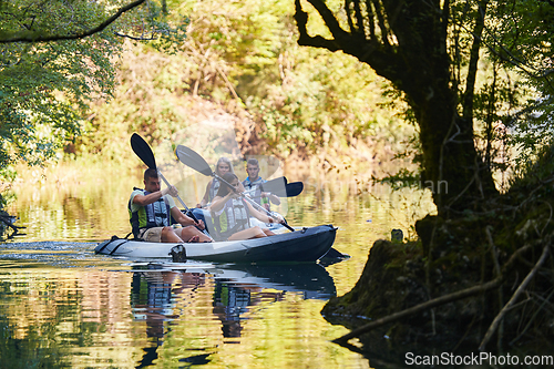 Image of A group of friends enjoying having fun and kayaking while exploring the calm river, surrounding forest and large natural river canyons