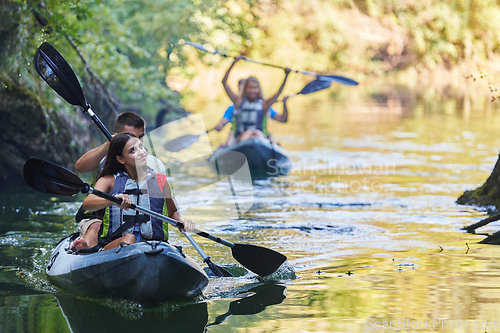 Image of A group of friends enjoying having fun and kayaking while exploring the calm river, surrounding forest and large natural river canyons