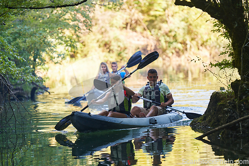 Image of A group of friends enjoying having fun and kayaking while exploring the calm river, surrounding forest and large natural river canyons