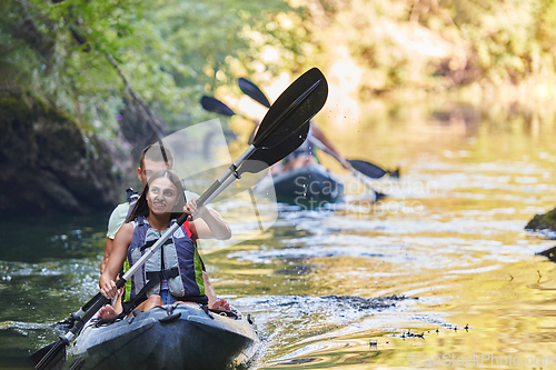 Image of A group of friends enjoying having fun and kayaking while exploring the calm river, surrounding forest and large natural river canyons