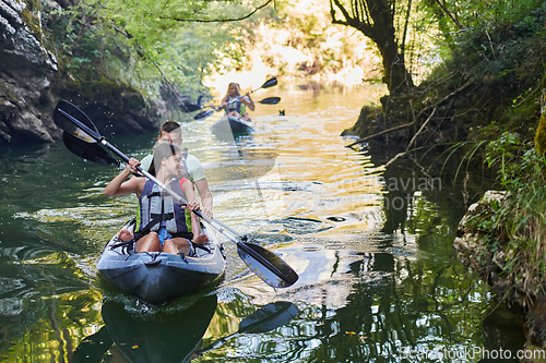 Image of A group of friends enjoying having fun and kayaking while exploring the calm river, surrounding forest and large natural river canyons