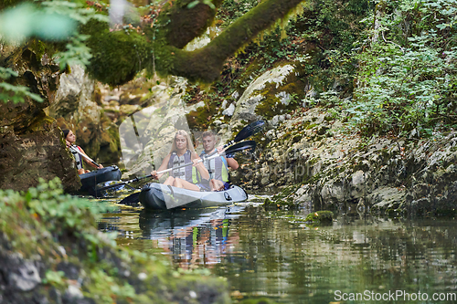 Image of A young couple enjoying an idyllic kayak ride in the middle of a beautiful river surrounded by forest greenery