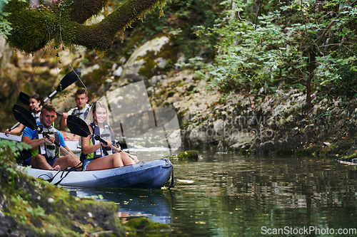 Image of A group of friends enjoying having fun and kayaking while exploring the calm river, surrounding forest and large natural river canyons