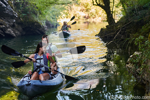 Image of A group of friends enjoying having fun and kayaking while exploring the calm river, surrounding forest and large natural river canyons