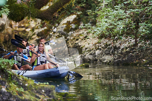 Image of A group of friends enjoying having fun and kayaking while exploring the calm river, surrounding forest and large natural river canyons