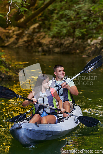 Image of A young couple enjoying an idyllic kayak ride in the middle of a beautiful river surrounded by forest greenery