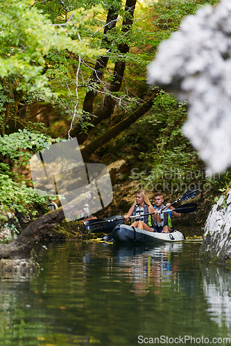 Image of A young couple enjoying an idyllic kayak ride in the middle of a beautiful river surrounded by forest greenery