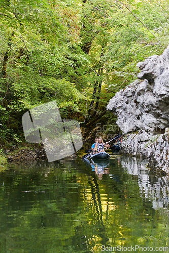 Image of A group of friends enjoying having fun and kayaking while exploring the calm river, surrounding forest and large natural river canyons