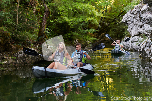 Image of A group of friends enjoying having fun and kayaking while exploring the calm river, surrounding forest and large natural river canyons