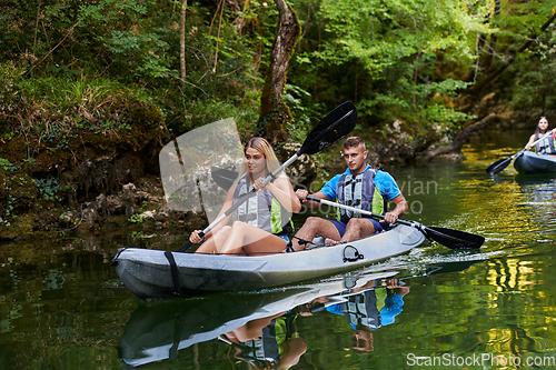 Image of A group of friends enjoying having fun and kayaking while exploring the calm river, surrounding forest and large natural river canyons