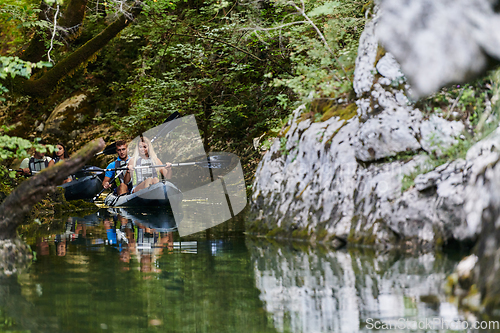 Image of A young couple enjoying an idyllic kayak ride in the middle of a beautiful river surrounded by forest greenery