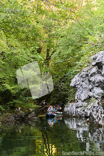 Image of A young couple enjoying an idyllic kayak ride in the middle of a beautiful river surrounded by forest greenery