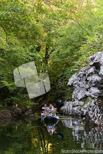 Image of A young couple enjoying an idyllic kayak ride in the middle of a beautiful river surrounded by forest greenery