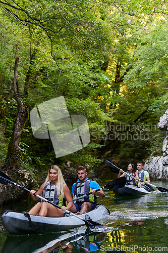 Image of A group of friends enjoying having fun and kayaking while exploring the calm river, surrounding forest and large natural river canyons