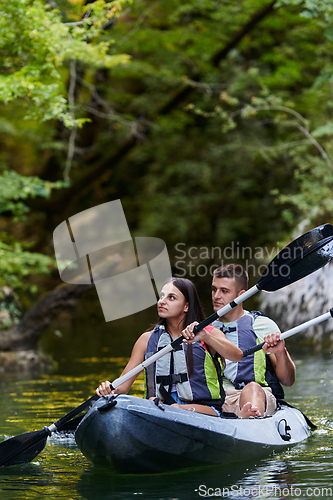 Image of A young couple enjoying an idyllic kayak ride in the middle of a beautiful river surrounded by forest greenery