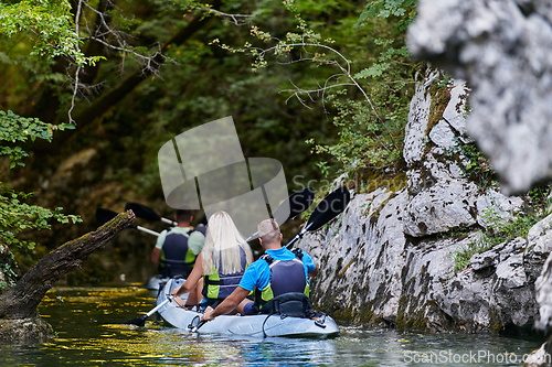 Image of A group of friends enjoying having fun and kayaking while exploring the calm river, surrounding forest and large natural river canyons