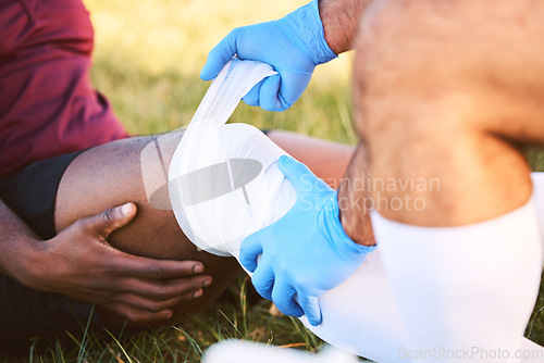 Image of Bandage, knee pain and injury, medic help athlete and sports accident on field with health and wellness. People outdoor, paramedic dressing wound and medical care with inflammation and fracture