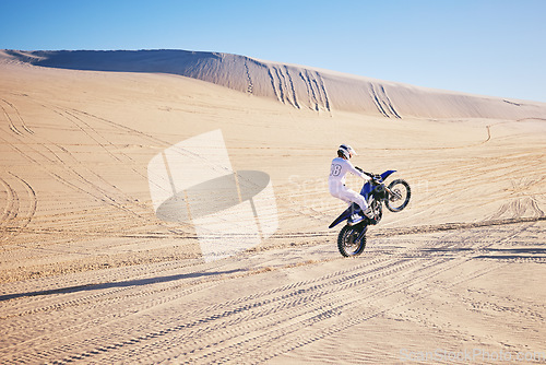 Image of Bike, sports and space with a man in the desert for adrenaline, adventure or training in nature. Moto, fitness and freedom with an athlete riding a motorcycle for energy or balance on sand in Dubai