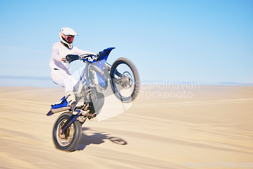 Image of Bike, sand and motion blur with a man in the desert for adrenaline, adventure or training in nature. Energy, speed and balance with a male sports athlete riding a motorcycle in a remote location