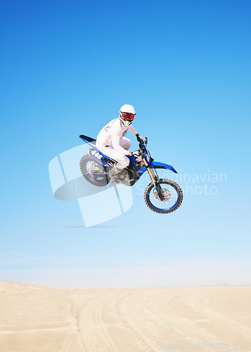 Image of Jump, motorbike and person in desert, blue sky with action and extreme sport, speed outdoor and mockup space. Adventure, fitness and motorcycle in air with stunt performance, freedom and challenge