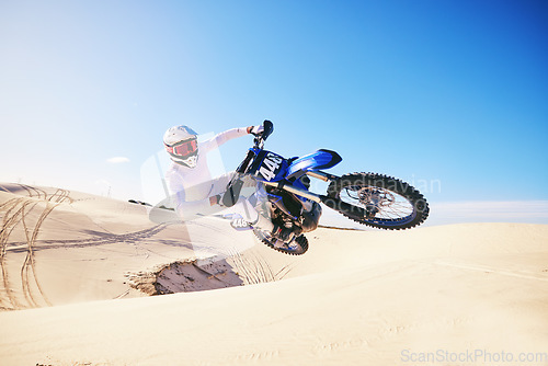 Image of Sand, motor sports and man in air with motorbike for adrenaline, adventure and freedom in desert. Action, extreme sport and male person on bike on dunes for training, exercise and race or challenge