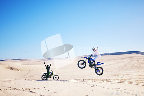 Image of Bike, winner and motivation with people in the desert for fitness or adrenaline while training. Motorcycle, support and celebration with athlete friends cheering a jump in Dubai for energy or freedom