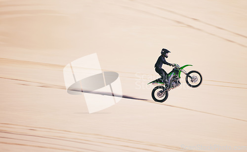 Image of Bike, sports and balance with a man in the desert for fitness or an adrenaline hobby on space. Motorcycle, training and summer with a male athlete riding a vehicle in Dubai for freedom or energy