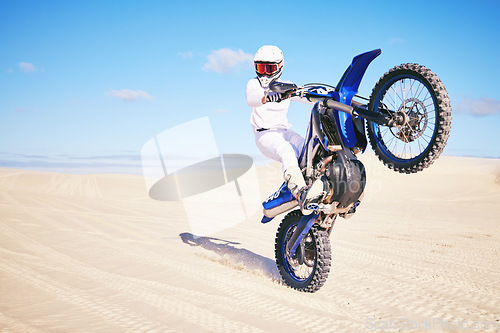 Image of Bike, freedom and balance with a man in the desert for fitness or an adrenaline hobby on a blue sky. Motorcycle, training and summer with a male sports athlete riding a vehicle in Dubai for energy