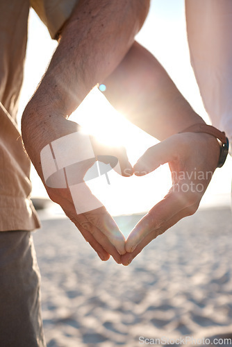 Image of Beach, hands and nature couple with heart icon for love, trust and outdoor freedom on travel vacation. Closeup, emoji health sign and summer people with sun flare, tropical holiday or wellness