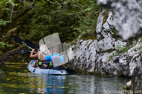 Image of A young couple enjoying an idyllic kayak ride in the middle of a beautiful river surrounded by forest greenery