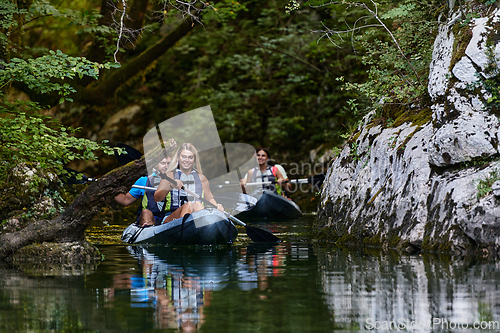 Image of A group of friends enjoying having fun and kayaking while exploring the calm river, surrounding forest and large natural river canyons