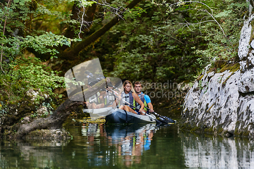 Image of A group of friends enjoying having fun and kayaking while exploring the calm river, surrounding forest and large natural river canyons