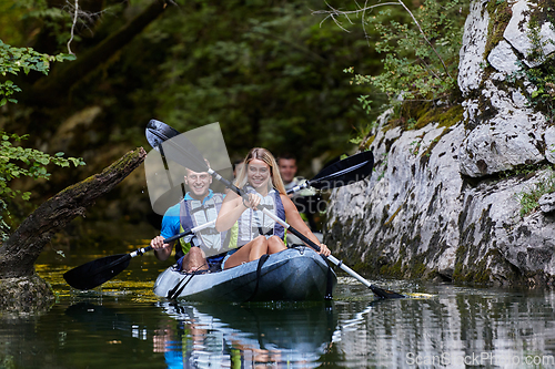 Image of A group of friends enjoying having fun and kayaking while exploring the calm river, surrounding forest and large natural river canyons