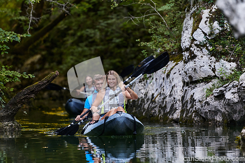 Image of A group of friends enjoying having fun and kayaking while exploring the calm river, surrounding forest and large natural river canyons