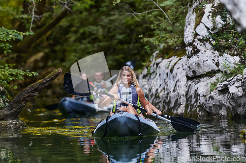 Image of A group of friends enjoying having fun and kayaking while exploring the calm river, surrounding forest and large natural river canyons